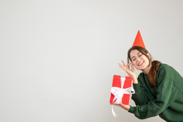 garota feliz com chapéu de festa fazendo sinal de ok em branco