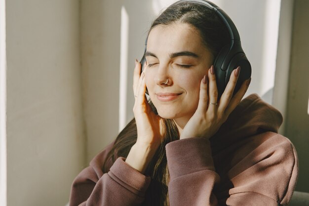 Garota feliz com fones de ouvido ouve música em casa