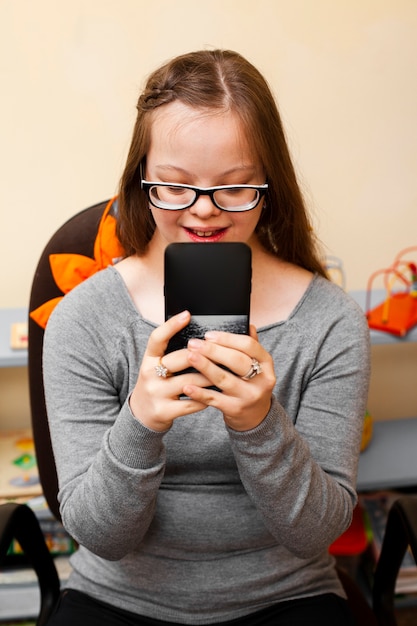 Foto grátis garota feliz com síndrome de down, olhando para o telefone