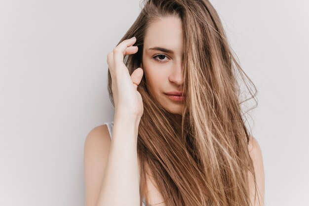 Garota feliz de olhos escuros, posando de manhã. foto da encantadora modelo feminina caucasiana, tocando seu cabelo escuro.