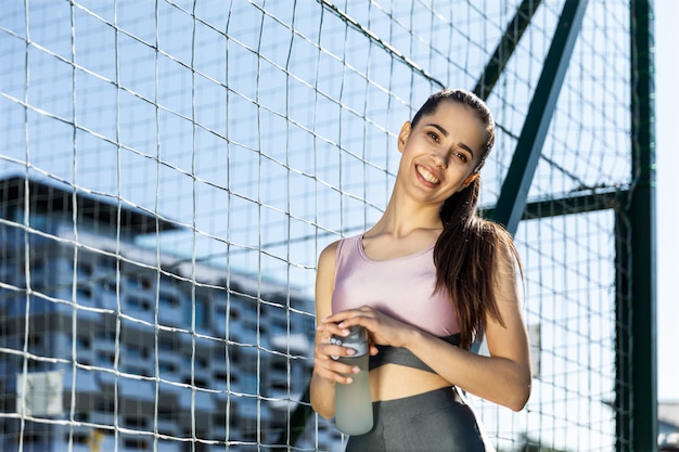 Garota fitness sorrindo mantém a garrafa de água