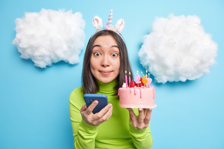 Foto grátis garota gosta de festa de aniversário posta fotos nas redes sociais segura bolo com velas acesas parece impressionada vestida com roupas casuais isoladas no azul
