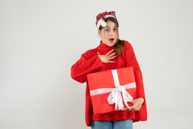 garota imaginou com chapéu de Papai Noel segurando um presente em branco