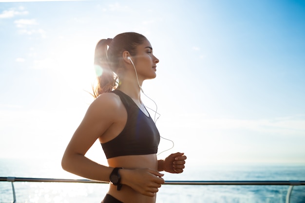 Garota jovem atraente fitness, movimentando-se com o mar