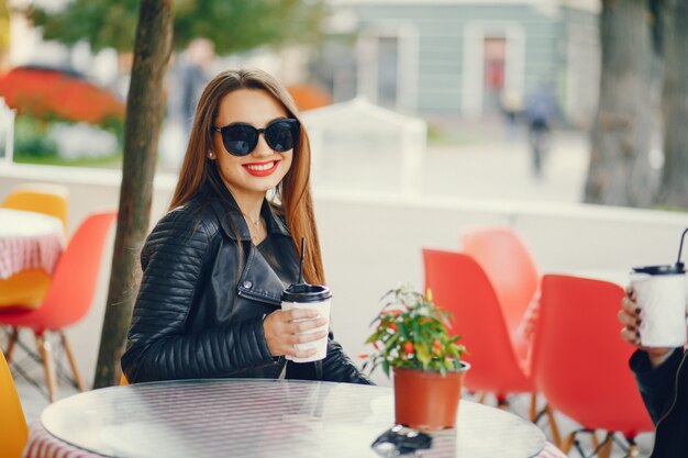 garota jovem e bonita, sentado em uma cidade de verão e beber um café