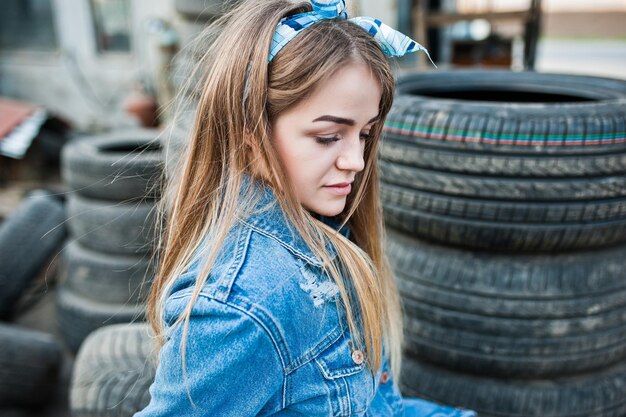 Garota jovem hippie na jaqueta jeans e lenço na cabeça na zona de montagem de pneus