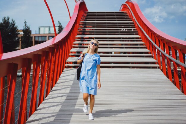 garota linda em um vestido azul posando na ponte