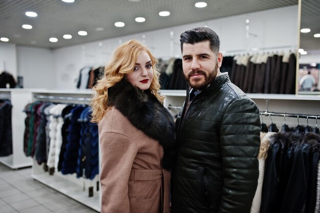 Garota loira de elegância com casaco de pele e homem turco estiloso na loja de casacos de pele e jaquetas de couro