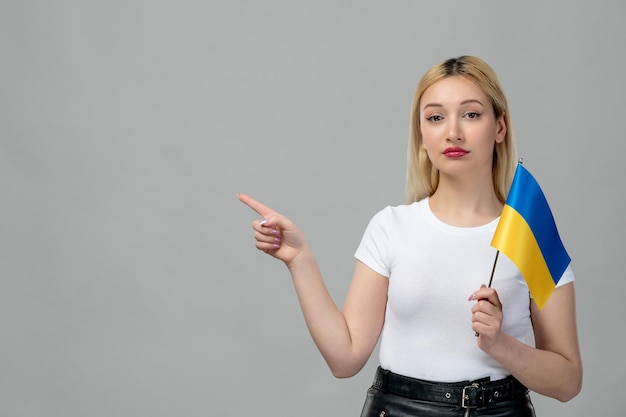 Garota loira do conflito russo da Ucrânia com batom vermelho e bandeira ucraniana apontando o dedo