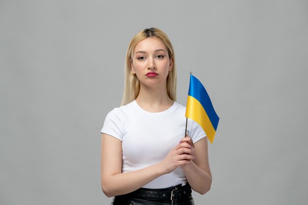 Garota loira do conflito russo da Ucrânia com batom vermelho e bandeira ucraniana chateada