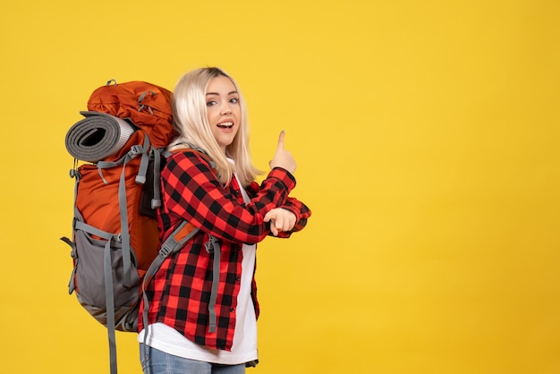 Foto grátis garota loira feliz de vista frontal com sua mochila apontando para trás