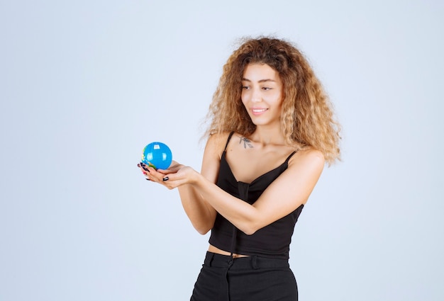 Garota loira segurando um mini globo e se sentindo positiva. Foto gratuita