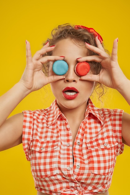 Foto grátis garota lúdica segurando macarons coloridos fazendo binóculos