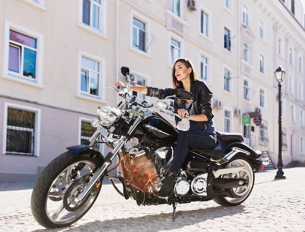 Garota motociclista em uma jaqueta de couro em uma motocicleta