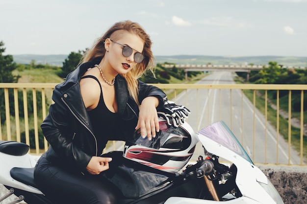 Garota motociclista em uma roupa de couro em uma motocicleta