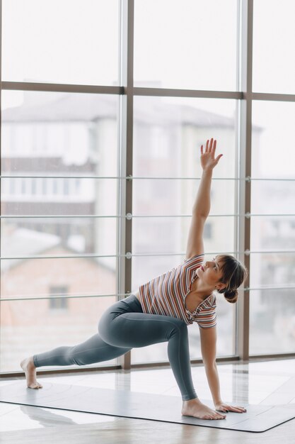 Garota muito atraente fazendo yoga em um quarto brilhante