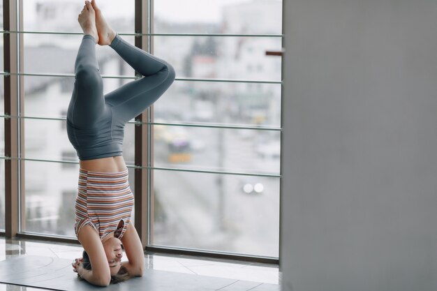 Garota muito atraente fazendo yoga em um quarto brilhante