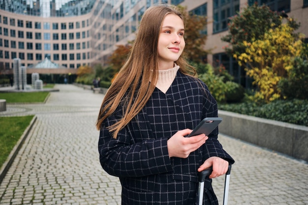 Garota muito casual feliz usando celular na rua da cidade