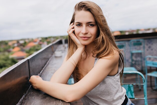 Garota muito pálida com penteado romântico, passar um tempo no café do telhado. Foto ao ar livre de uma incrível jovem relaxando no fim de semana de primavera.