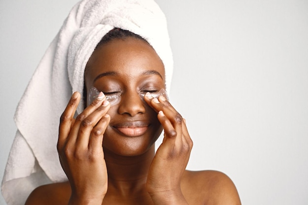 Garota negra com toalha na cabeça tem tapa-olhos isolados no fundo branco