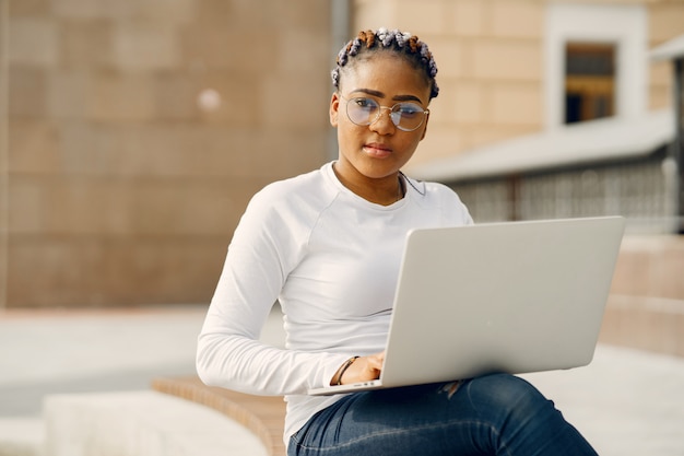 Garota negra em uma cidade de verão com laptop