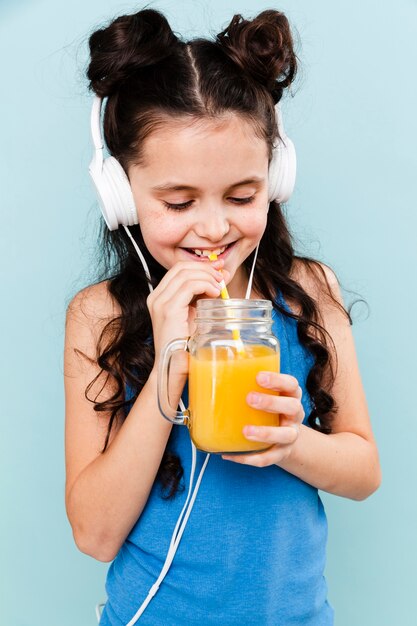 Garota ouvindo música e bebendo suco