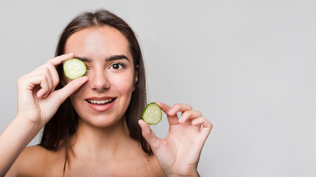 Garota posando com fatias de pepino