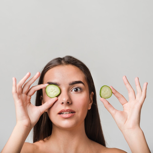 Garota posando com fatias de pepino