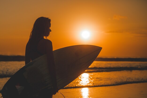 garota posando com uma placa ao pôr do sol