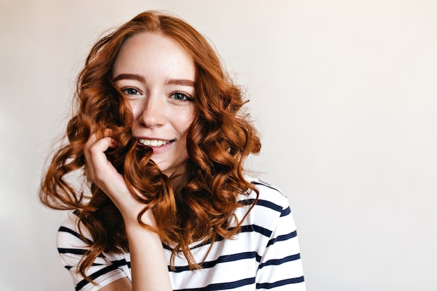 Foto grátis garota ruiva de olhos azuis posando com um sorriso feliz. tiro interno da incrível senhora ruiva isolada.