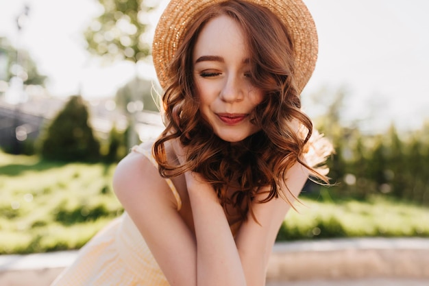 Garota ruiva relaxada sorrindo com os olhos fechados foto ao ar livre de mulher ruiva romântica em cabelo elegante posando no fundo da natureza