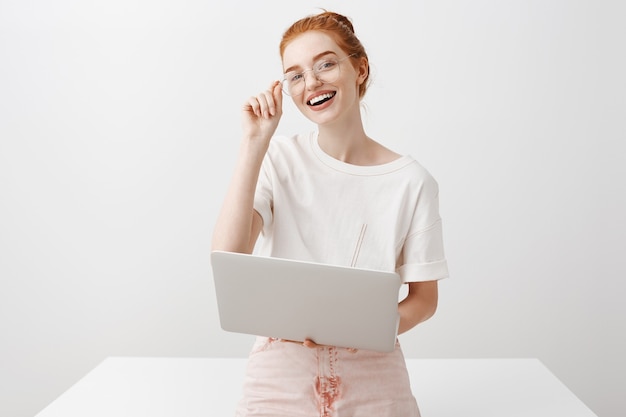 Garota ruiva sorridente usando laptop e olhando