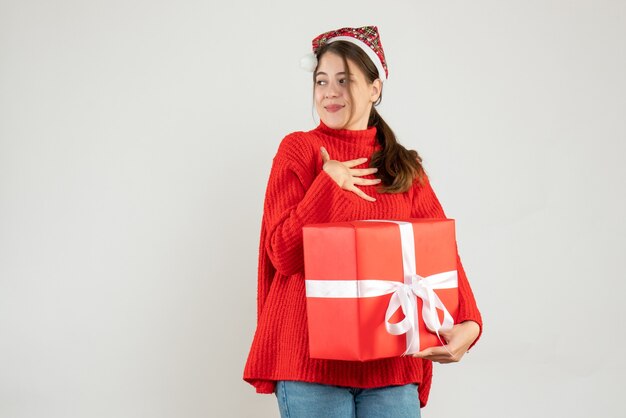 garota satisfeita com chapéu de Papai Noel segurando um presente em branco