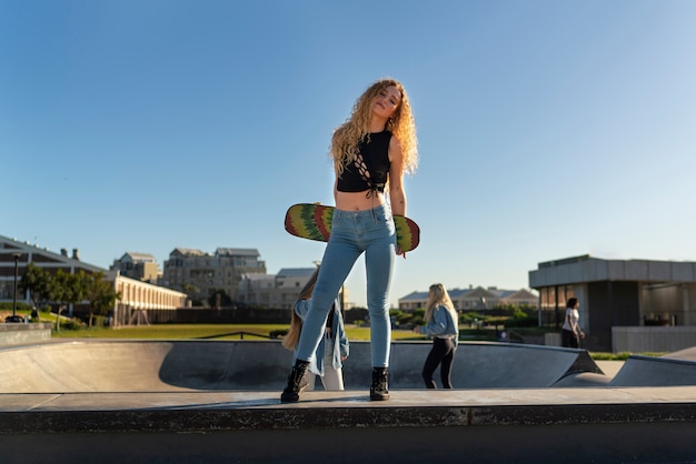 Foto grátis garota segurando a vista frontal do skate colorido