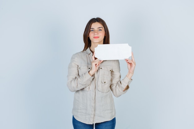 Garota segurando uma moldura de papel na camisa e parecendo confiante