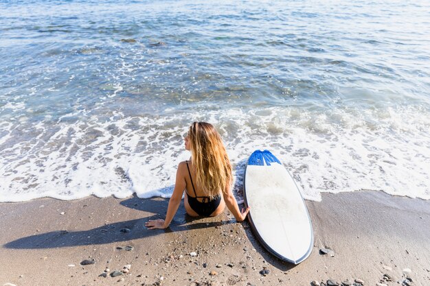 Garota sexy com prancha de surf na praia