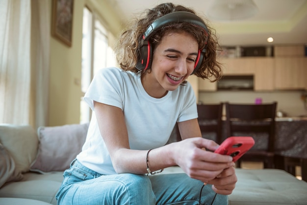 Garota sorridente com fones de ouvido enviando mensagens no telefone