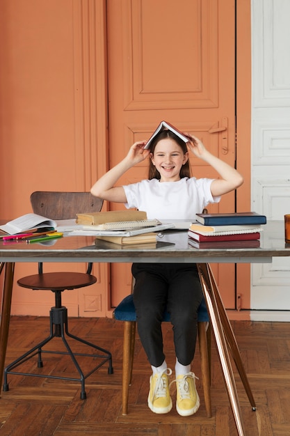 Foto grátis garota sorridente de tiro completo sentada na mesa