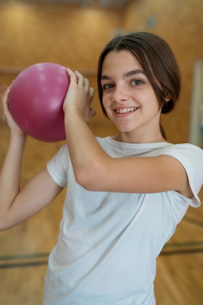 Garota sorridente de tiro médio com bola de basquete