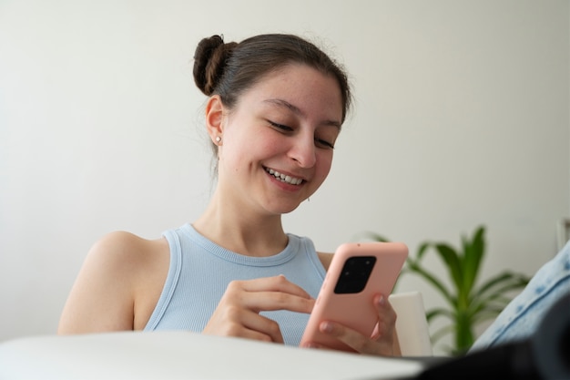 Garota sorridente de tiro médio segurando smartphone