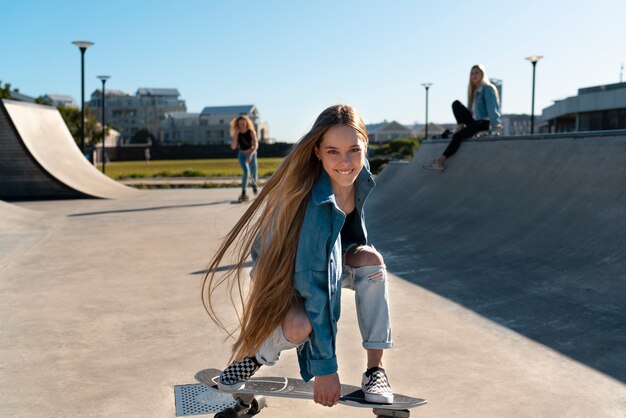 Garota sorridente de vista frontal no skate ao ar livre