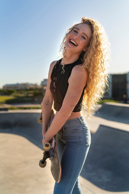 Garota sorridente de vista lateral no parque de skate