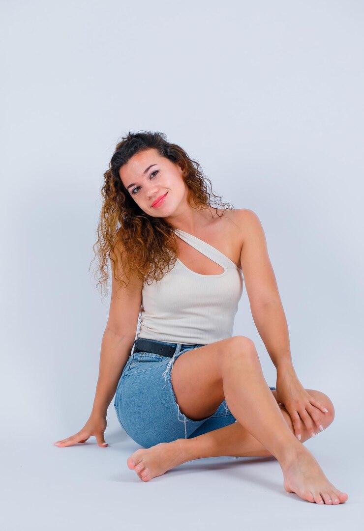 Foto grátis garota sorridente está olhando para a câmera sentada no chão no fundo branco
