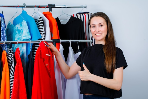 Garota sorridente está segurando a blusa e mostrando o gesto perfeito no fundo da roupa