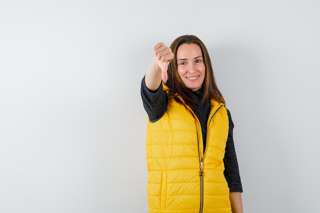 Garota sorridente mostrando um polegar para baixo no fundo branco