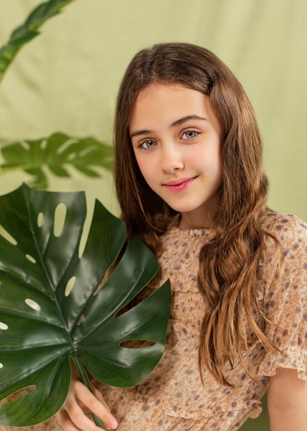 Garota sorridente posando com planta monstera