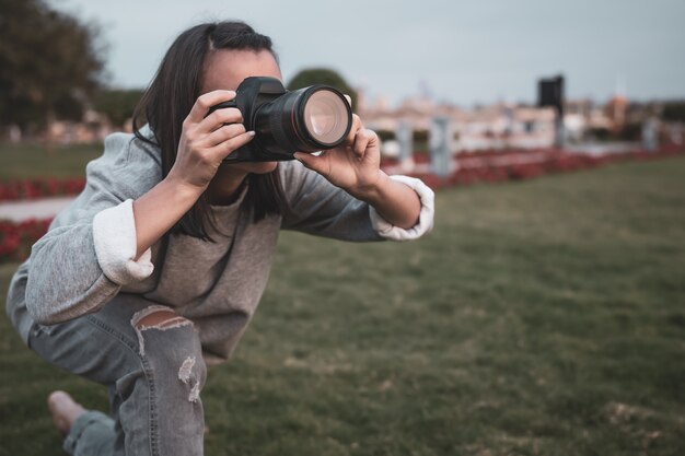 Garota tira uma foto com uma câmera SLR profissional no verão ao ar livre.