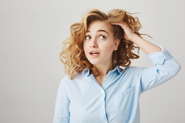 Foto grátis garota tocando cabelo encaracolado, decidindo ir cabeleireiro