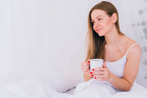 Garota tomando café na cama