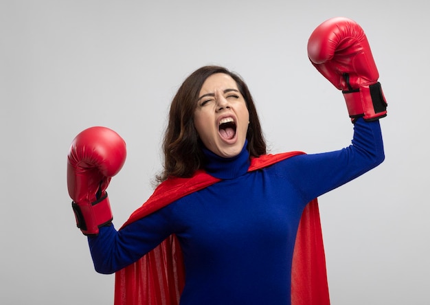 Garota zangada super-heroína caucasiana com capa vermelha e usando luvas de boxe fica com as mãos levantadas